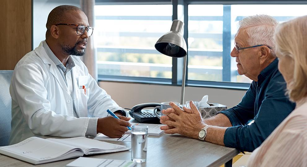 Older adult couple speaking with doctor in office