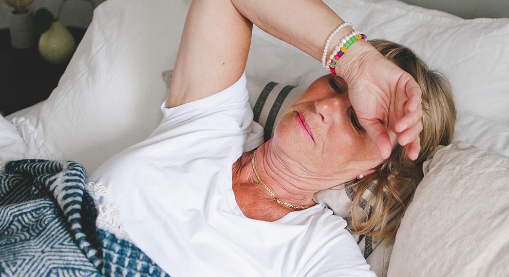 Older adult woman feeling fatigued lying down in bed
