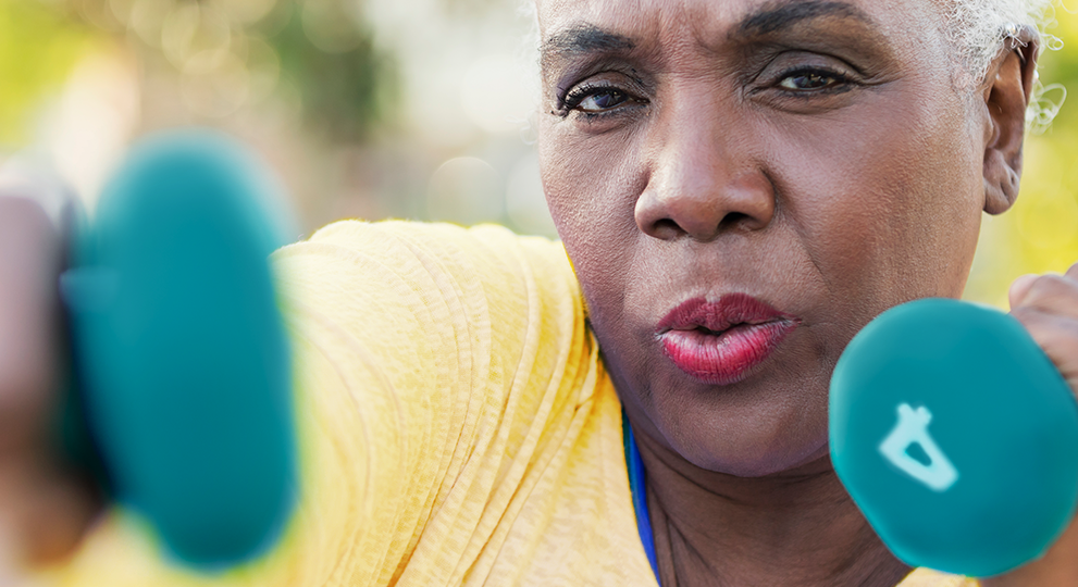 Older woman punching the air like a boxer while holding four pound weights